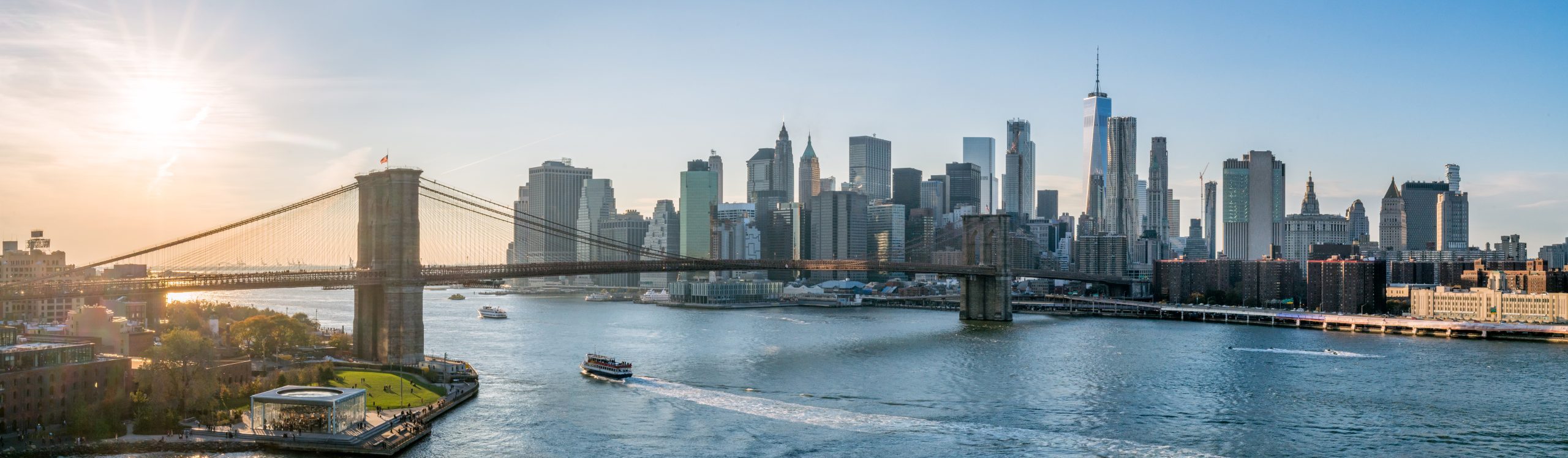 New York City skyline panorama at sunset with Brooklyn Bridge.